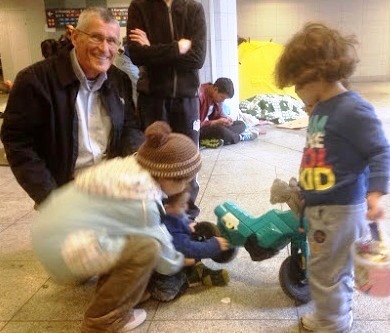 Niños refugiados con el padre Frank se entretienen en la estación. (Foto: Eurobishop).